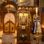 Greek Orthodox church interior with candles and Easter decorations.